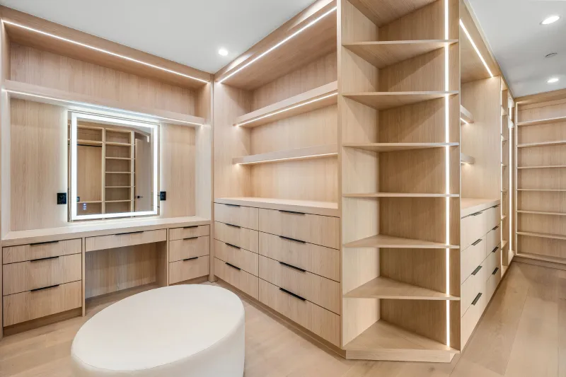 Modern walk-in closet with wooden shelves and vanity mirror